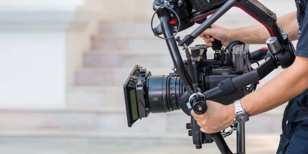 Real estate photographer and videographer comparing a DSLR and gimbal camera inside a bright Sydney home interior